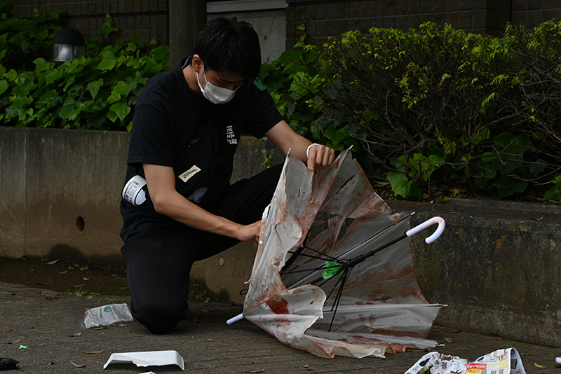 血まみれのビニール傘や散乱したゴミは、美術スタッフが準備した小道具です。