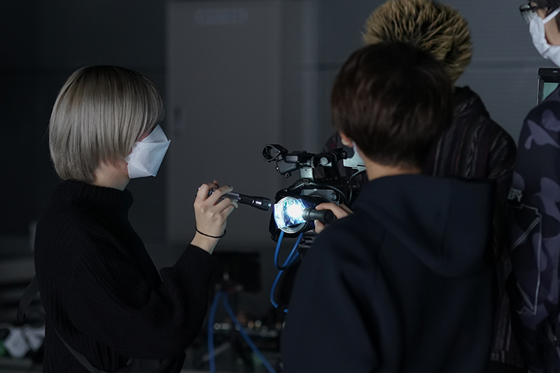 カメラのレンズにカラーテープを貼り、光を当てることで、映像の効果を出す手法