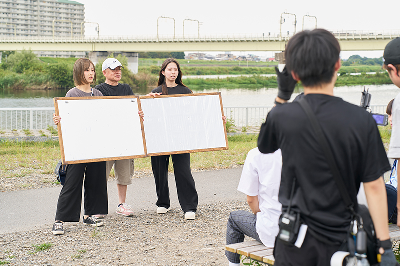 <p>照明スタッフはレフ板を持って、出演者の顔の明るさなどを調整</p>